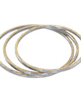Three gold bracelets stacked on a white background