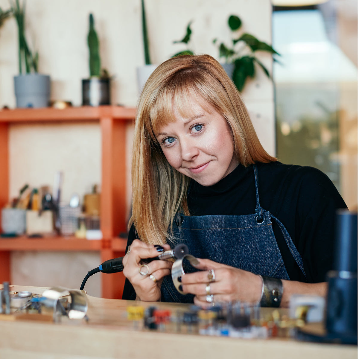 custom Denver CO jeweler and designer Kate Maller sitting at her work bench working on a silver bracelet