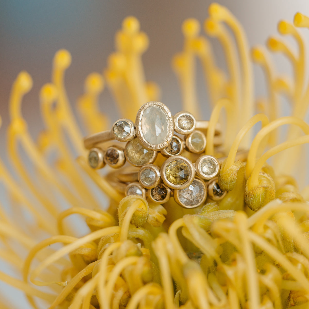 stack of four multi-stone bezel set engagement ring custom jewelry designs done by the Kate Maller Denver CO jewelry studio
